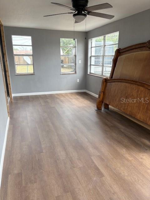 unfurnished bedroom with ceiling fan, baseboards, and wood finished floors