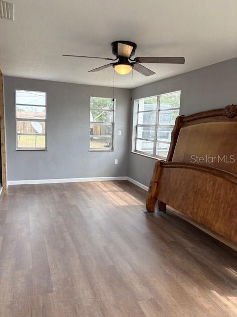 bedroom with visible vents, a ceiling fan, baseboards, and wood finished floors