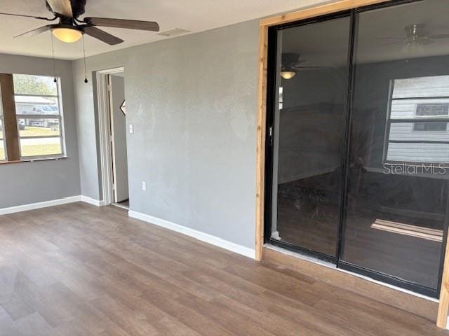 empty room featuring visible vents, a ceiling fan, baseboards, and wood finished floors