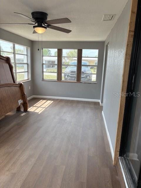 unfurnished bedroom with ceiling fan, visible vents, baseboards, and wood finished floors