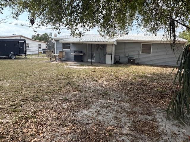 rear view of house featuring a patio area, central air condition unit, metal roof, and a yard