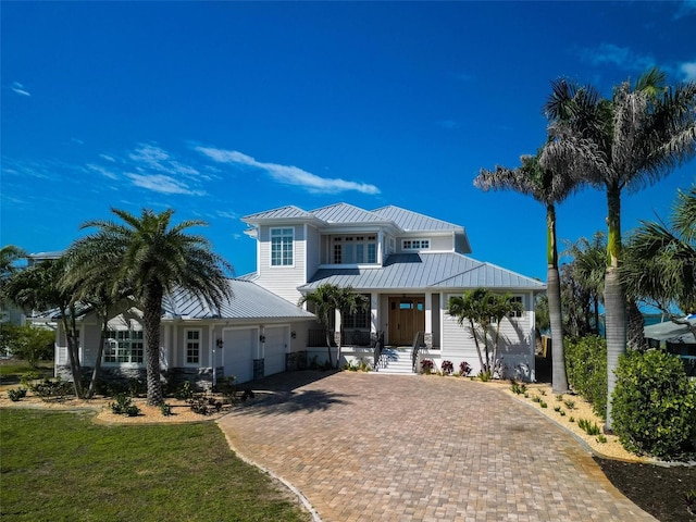 view of front of house featuring covered porch, metal roof, decorative driveway, an attached garage, and a standing seam roof