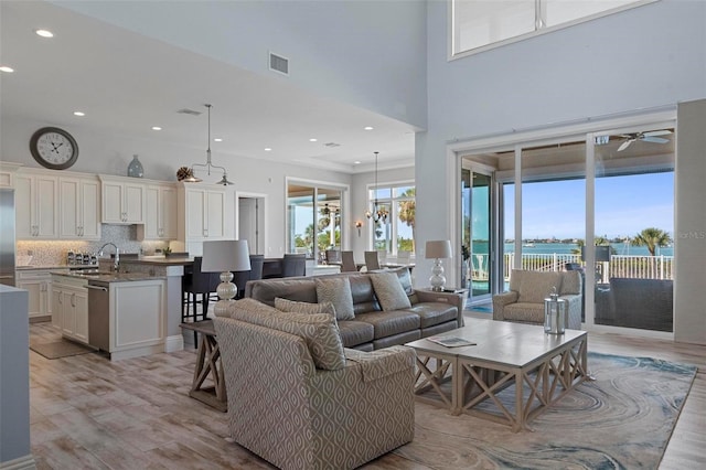 living area with recessed lighting, light wood-style flooring, and a towering ceiling