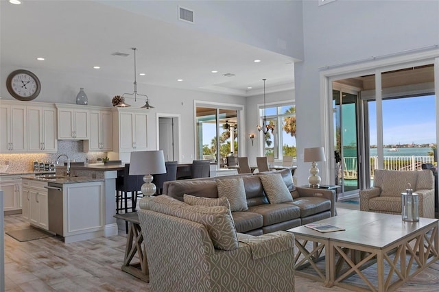 living room featuring recessed lighting, visible vents, a high ceiling, and light wood finished floors