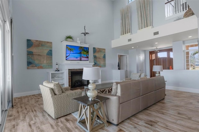 living room with a fireplace, light wood-style floors, visible vents, and baseboards