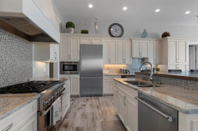 kitchen featuring a sink, tasteful backsplash, white cabinetry, built in appliances, and extractor fan