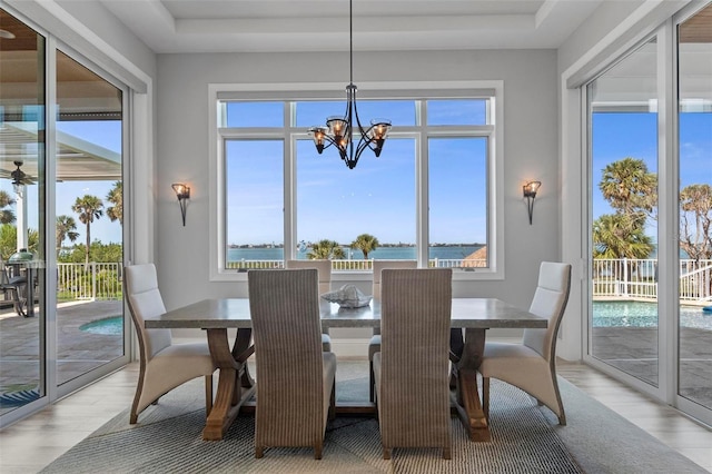 dining space with a chandelier, light wood-type flooring, and a water view