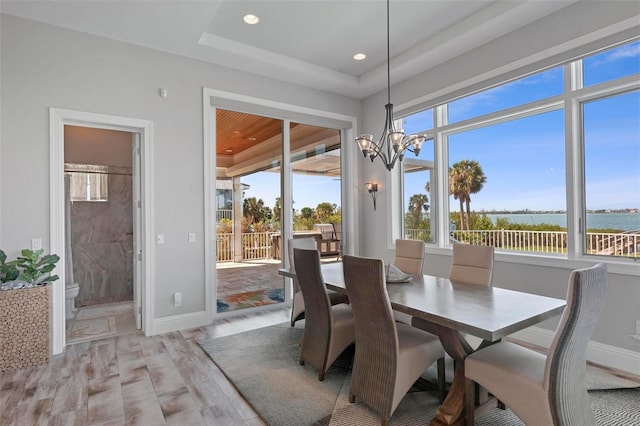 dining area with a wealth of natural light, baseboards, an inviting chandelier, and light wood-style flooring