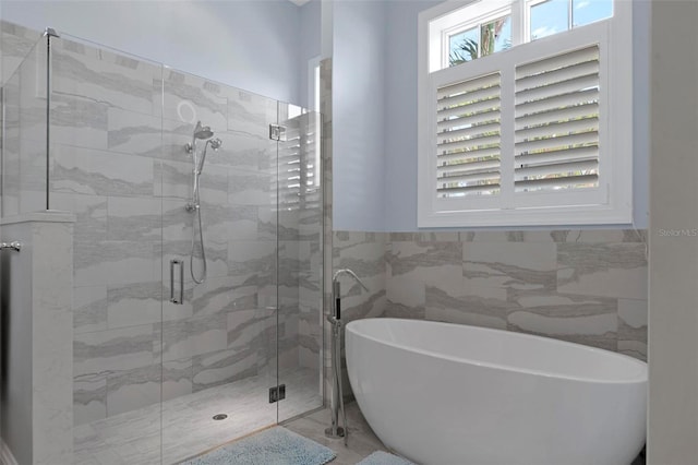 full bathroom with a soaking tub, a shower stall, and tile walls