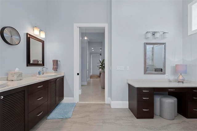 bathroom with marble finish floor, vanity, and baseboards