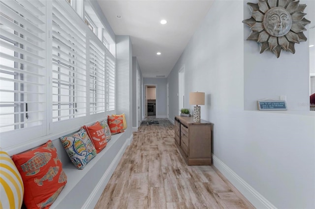 hallway featuring light wood-style flooring, recessed lighting, and baseboards