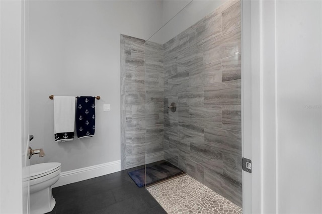 full bathroom featuring toilet, tiled shower, and baseboards