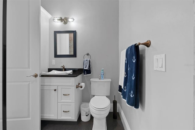 half bath with vanity, toilet, and baseboards