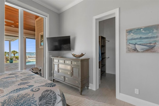 bedroom with access to exterior, crown molding, wood finished floors, and baseboards