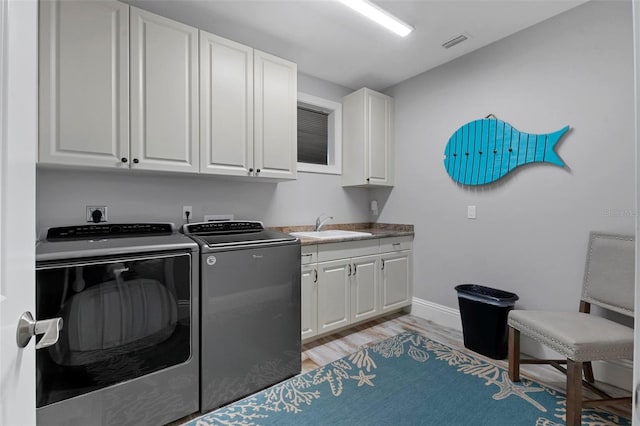 laundry room with visible vents, a sink, light wood-style flooring, cabinet space, and separate washer and dryer