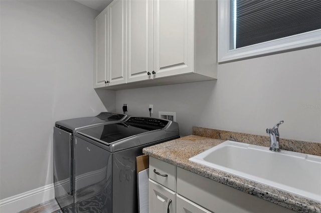 clothes washing area featuring a sink, cabinet space, and washer and clothes dryer