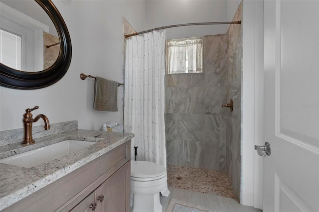 full bath featuring a tile shower, toilet, and vanity