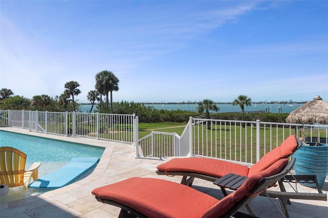 outdoor pool with a yard, a patio area, and a water view