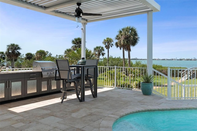 view of patio / terrace with grilling area, a water view, and exterior kitchen