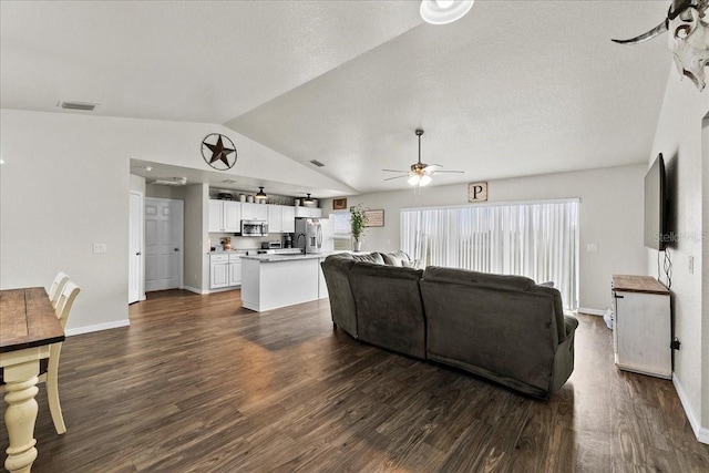 living area featuring vaulted ceiling, visible vents, dark wood-style flooring, and ceiling fan