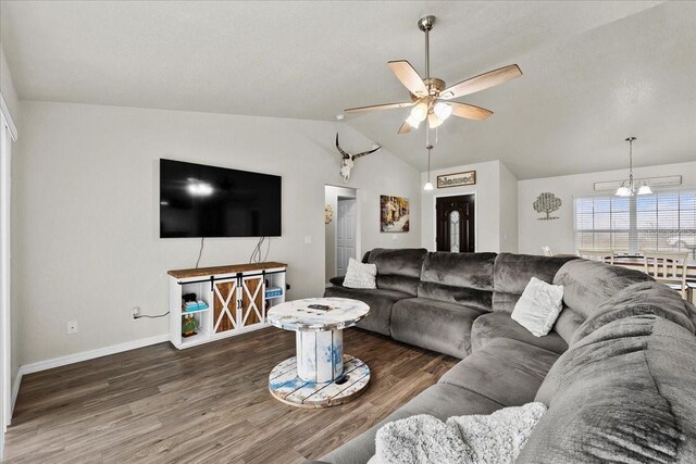 living room with baseboards, ceiling fan with notable chandelier, wood finished floors, and vaulted ceiling