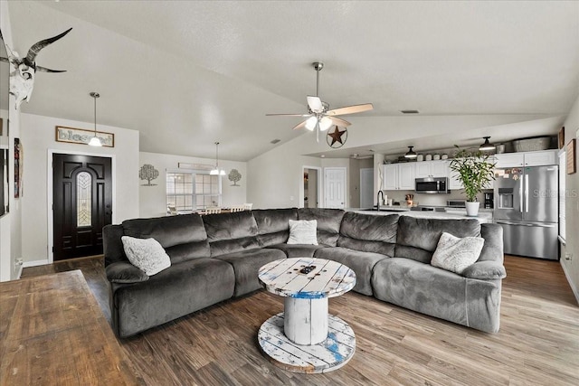 living room featuring light wood finished floors, a ceiling fan, and vaulted ceiling