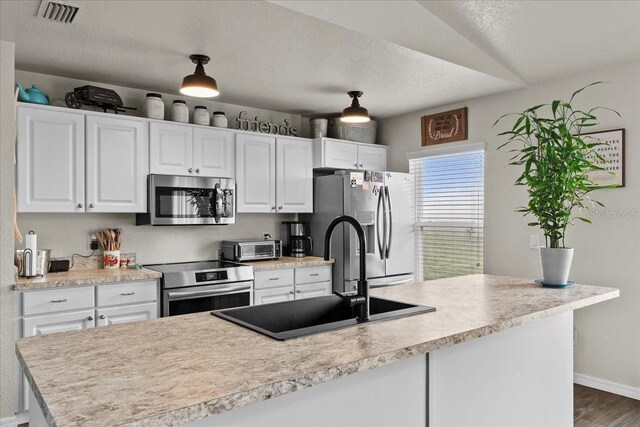 kitchen featuring a sink, stainless steel appliances, visible vents, and white cabinetry