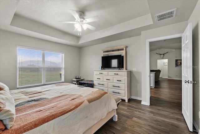 bedroom with dark wood-style floors, visible vents, and a raised ceiling