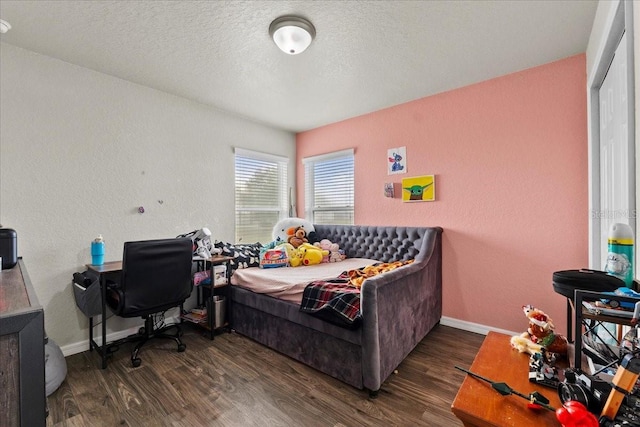 bedroom featuring wood finished floors, baseboards, a textured wall, and a textured ceiling