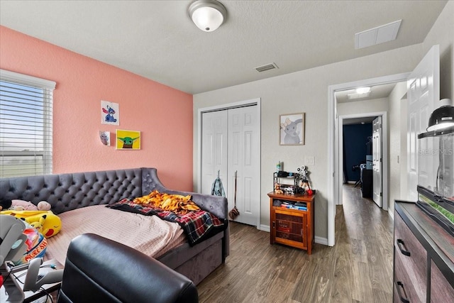 bedroom featuring a closet, visible vents, baseboards, and wood finished floors