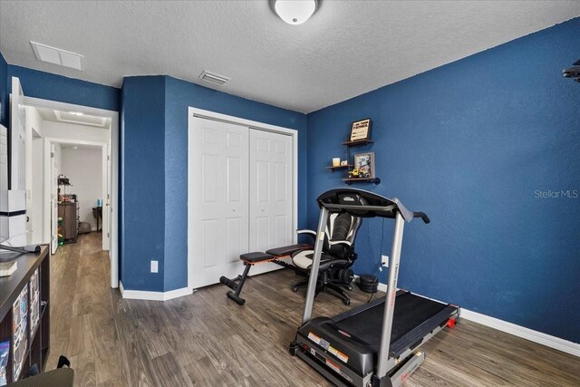 exercise area with visible vents, baseboards, and wood finished floors