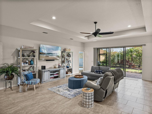 living area with visible vents, baseboards, a tray ceiling, recessed lighting, and a ceiling fan