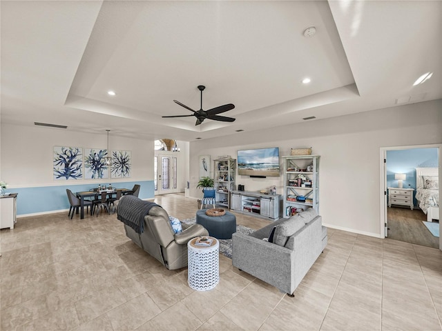 living room with light tile patterned floors, recessed lighting, a raised ceiling, and baseboards