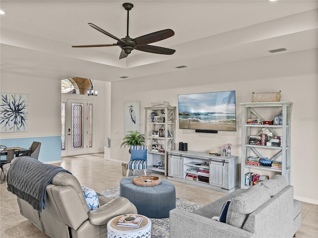 living area featuring baseboards, visible vents, a tray ceiling, recessed lighting, and ceiling fan with notable chandelier