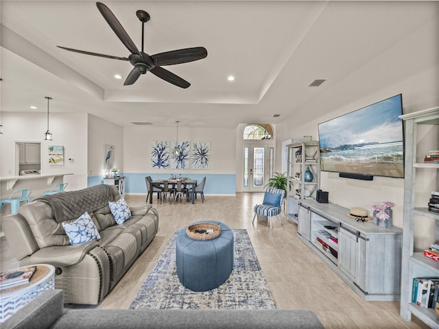 living area featuring recessed lighting, visible vents, a raised ceiling, and ceiling fan