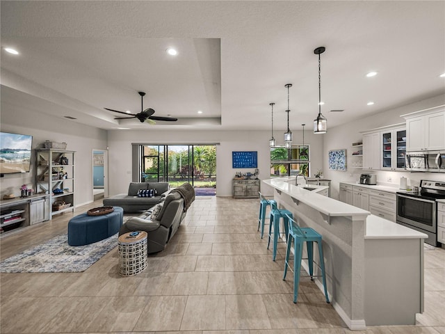 living room with a ceiling fan, a tray ceiling, recessed lighting, and a textured ceiling