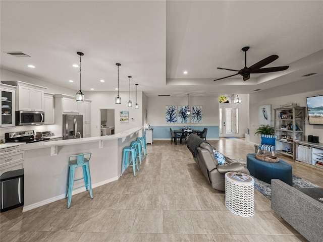 living area with a ceiling fan, recessed lighting, visible vents, and baseboards