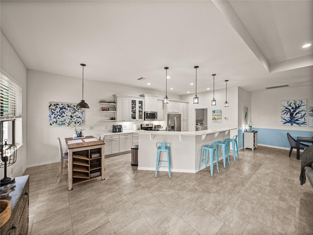 kitchen featuring a breakfast bar area, open shelves, recessed lighting, appliances with stainless steel finishes, and white cabinetry