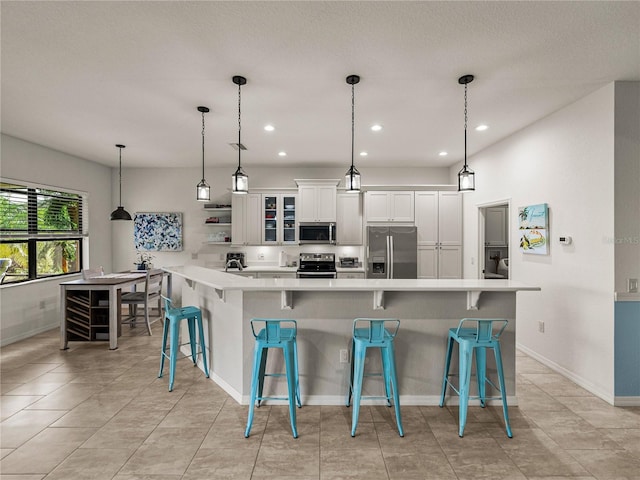 kitchen featuring a kitchen breakfast bar, appliances with stainless steel finishes, white cabinets, and light countertops