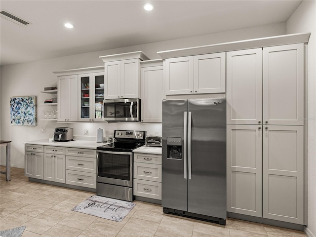 kitchen with visible vents, recessed lighting, light countertops, glass insert cabinets, and appliances with stainless steel finishes