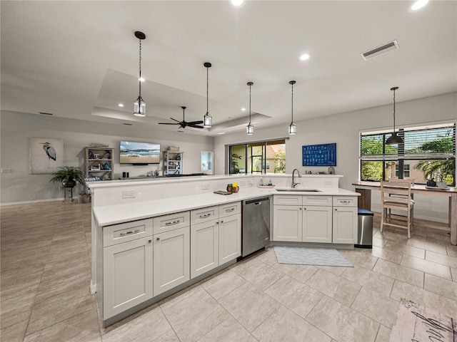 kitchen with visible vents, a sink, a tray ceiling, stainless steel dishwasher, and light countertops