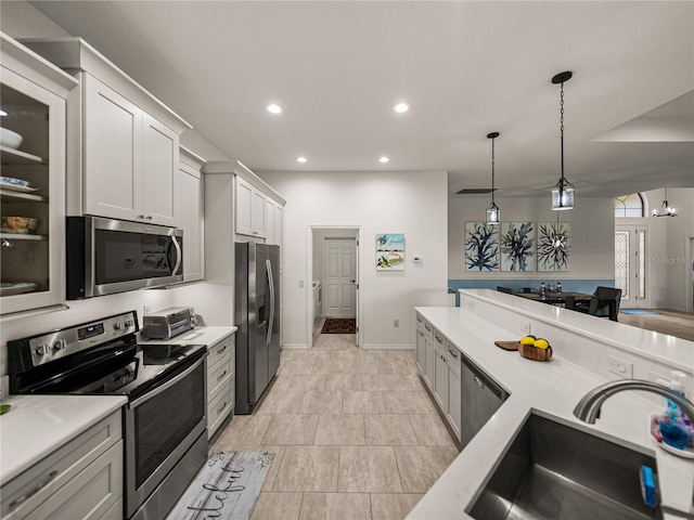 kitchen featuring recessed lighting, a sink, hanging light fixtures, light countertops, and stainless steel appliances