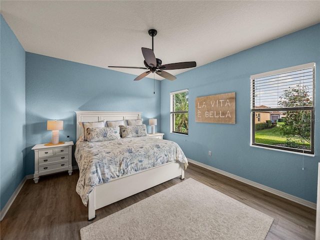 bedroom with a ceiling fan, baseboards, and dark wood-style flooring