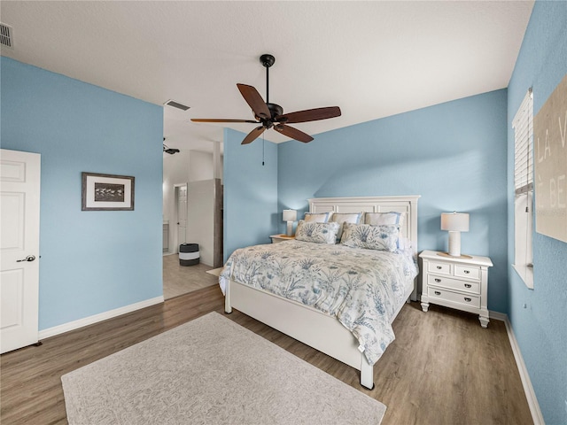 bedroom with a ceiling fan, wood finished floors, visible vents, and baseboards