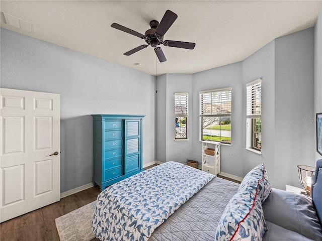 bedroom featuring visible vents, baseboards, ceiling fan, and wood finished floors