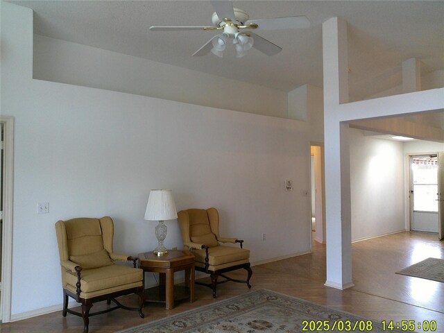 living area featuring baseboards, wood finished floors, and a ceiling fan