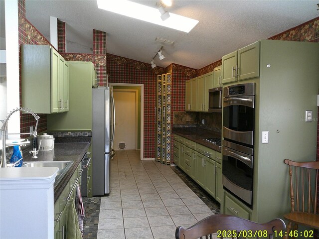 kitchen with dark countertops, stainless steel appliances, lofted ceiling, and green cabinetry