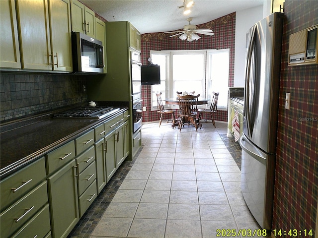 kitchen with light tile patterned floors, a ceiling fan, appliances with stainless steel finishes, green cabinets, and dark countertops