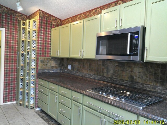 kitchen with wallpapered walls, light tile patterned flooring, appliances with stainless steel finishes, and a textured ceiling