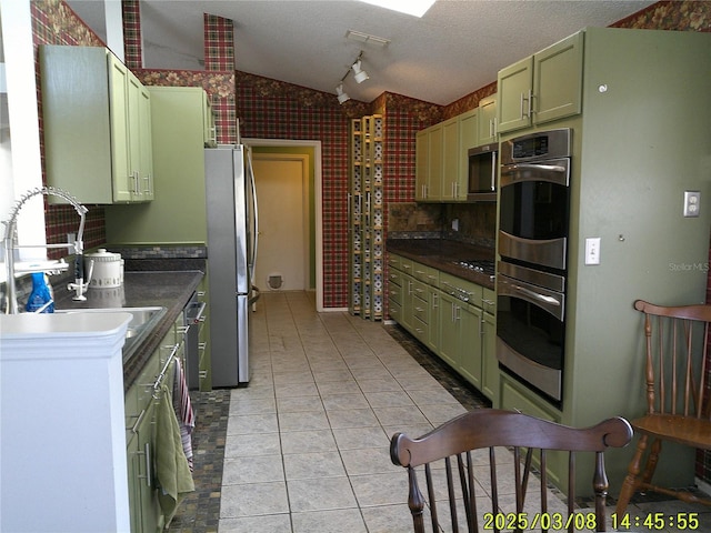 kitchen featuring green cabinetry, stainless steel appliances, lofted ceiling, and a sink